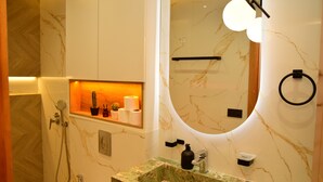 A modern bathroom with a marble sink, a built-in shower, and a mirror with integrated lighting.