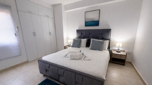 Un dormitorio con cama, mesitas de noche, armario y un cuadro en la pared.