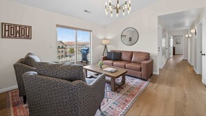 Un salon avec des meubles à motifs, une table basse, un canapé et une grande fenêtre donnant sur un beau paysage.