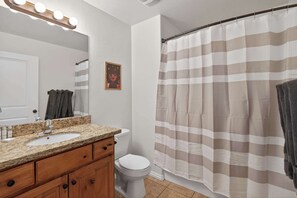 Une salle de bain équipée d’un meuble-lavabo, d’un lavabo, d’un miroir et d’un rideau de douche.