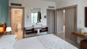 A hotel room with a bed, a bathroom, a TV, and a desk with a lamp. - Imperial Suite 2 Bedroom Ocean View With Kitchen (Sosúa)