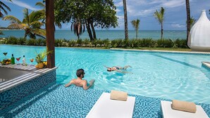 A pool area with two lounge chairs, a large decorative vase, and a view of the ocean. - Imperial Suite 2 Bedroom Ocean View With Kitchen (Sosúa)