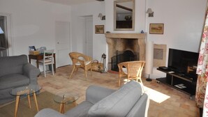 Una sala de estar con chimenea, un sofá, un televisor y sillas de mimbre.