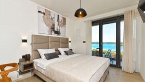 A bedroom with a large bed, a nightstand, a lamp, a chair, and a view of the sea through a sliding door. - House 2417/192118 (Istria - Medulin), 250m from the beach (Medulin)