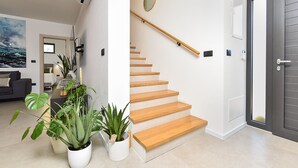 A modern interior with a wooden staircase, potted plants, and a grey door. - House 2417/192118 (Istria - Medulin), 250m from the beach (Medulin)