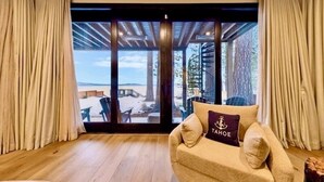 Ein Zimmer mit einer Couch, einem Fenster mit Vorhängen und Blick auf einen Außenbereich mit einer Treppe.