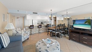 Un soggiorno moderno con divano, poggiapiedi e zona pranzo con sedie e televisore.