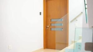Um interior moderno com porta de madeira, escada e guarda-corpo de vidro.