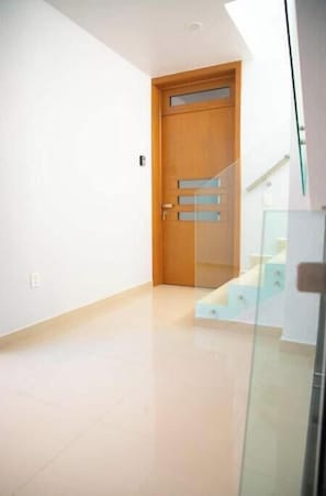 A modern interior with a wooden door, a staircase, and a glass railing.