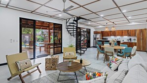 A spacious living area with a modern kitchen, a spiral staircase, and a view of an outdoor pool area. - Villa Ave del Paraiso, 7-bedroom Bed & Breakfast Villa in Playa Avellanas (Playa Avellanas)