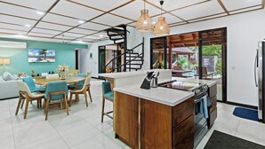 A modern kitchen with a central island, wooden cabinetry, and a built-in stove. - Villa Ave del Paraiso, 7-bedroom Bed & Breakfast Villa in Playa Avellanas (Playa Avellanas)