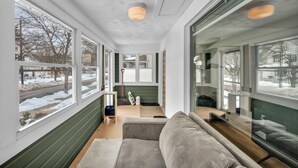 Un interior moderno con ventanas amplias, un sofá gris y suelo de madera.