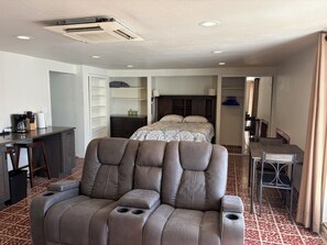 A hotel room with a sofa, a bed, a desk, and a wardrobe. - Large, well equipped Studio with Queen Bed and new bathroom. (Tucson)