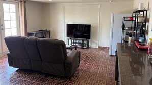 A living room with a sofa, a television, a kitchen area with a refrigerator, and a dining table. - Large, well equipped Studio with Queen Bed and new bathroom. (Tucson)