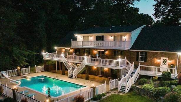 A two-story house with a swimming pool, multiple balconies, and a well-lit outdoor area. - The SoMD Diamond House (Mechanicsville)