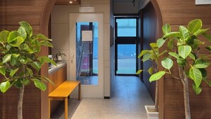 Un pasillo con un banco de madera, plantas en macetas y un cartel que dice 'LOCKERS'.