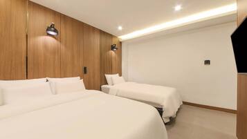 Habitación de hotel con dos camas, paneles de madera, una lámpara de pared y una luz en el techo.