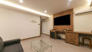 Una sala de estar moderna con una mesa de centro de vidrio, un sofá, un televisor montado en la pared y un mueble de madera.