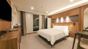 Una habitación de hotel con cama, escritorio y espejo.