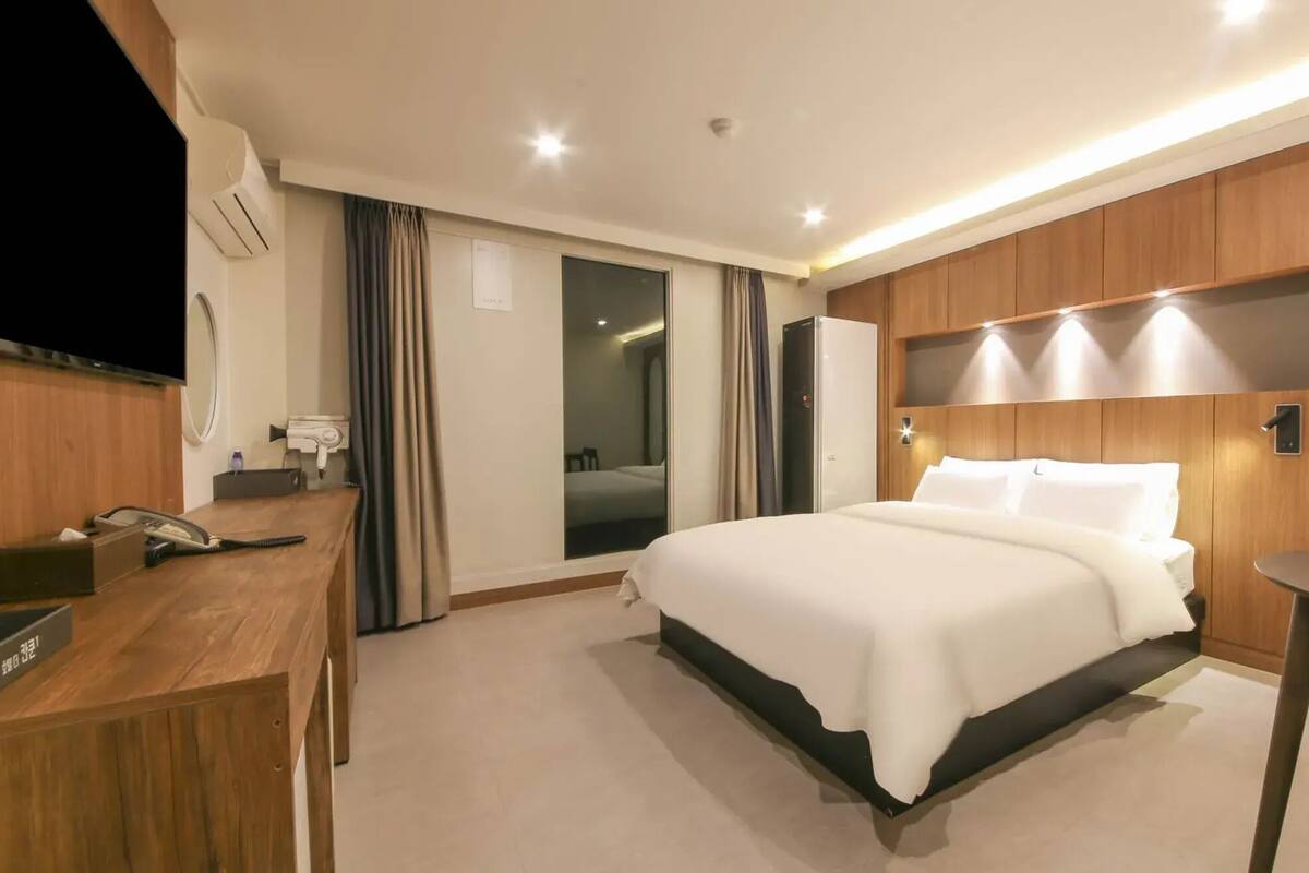 A hotel room with a bed, desk, and a mirror.
