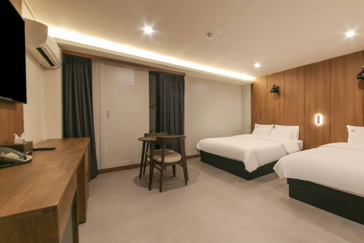 A hotel room with two beds, a desk, and a chair.