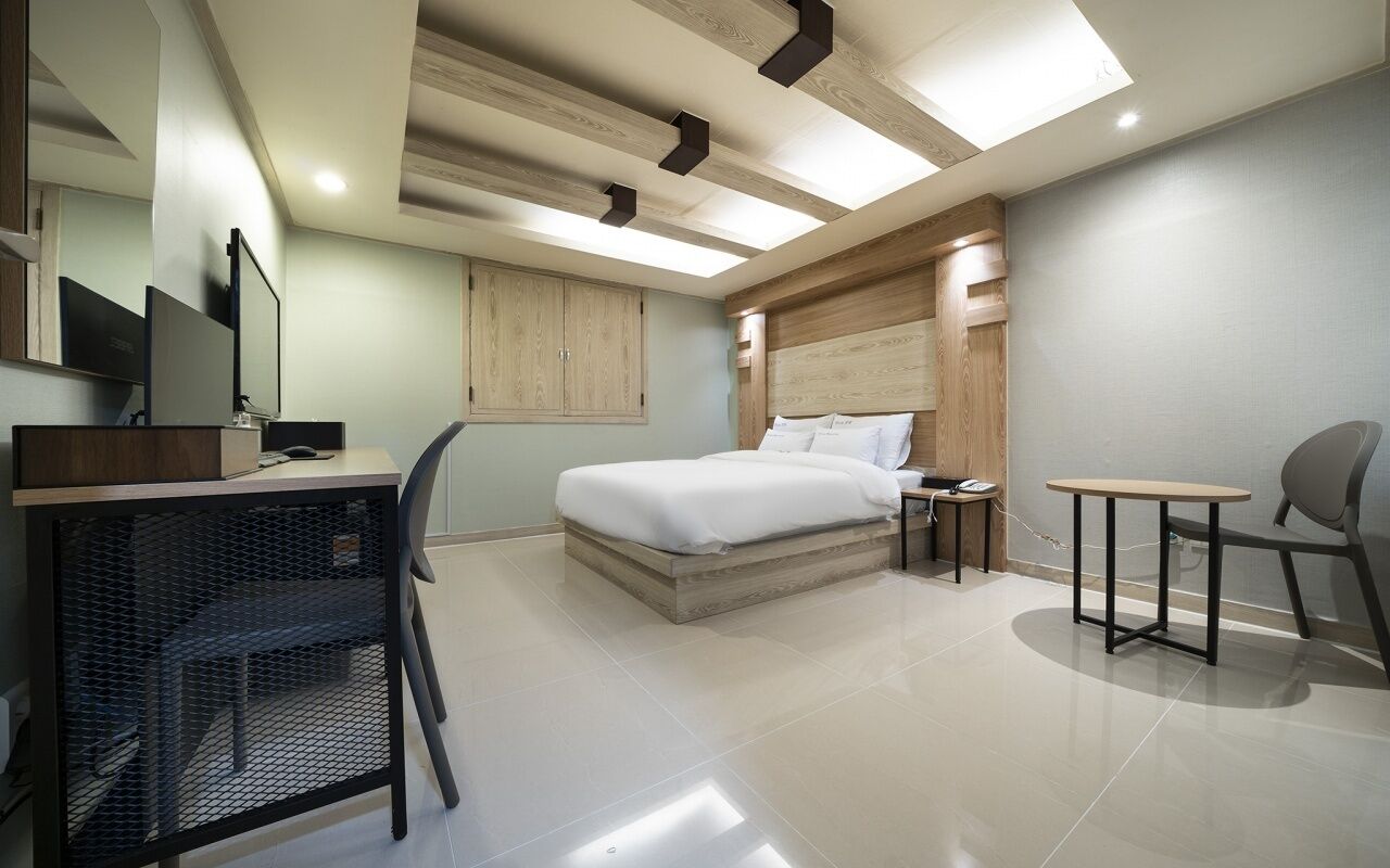 Una habitación de hotel moderna con cama, escritorio, silla y una pequeña mesa.
