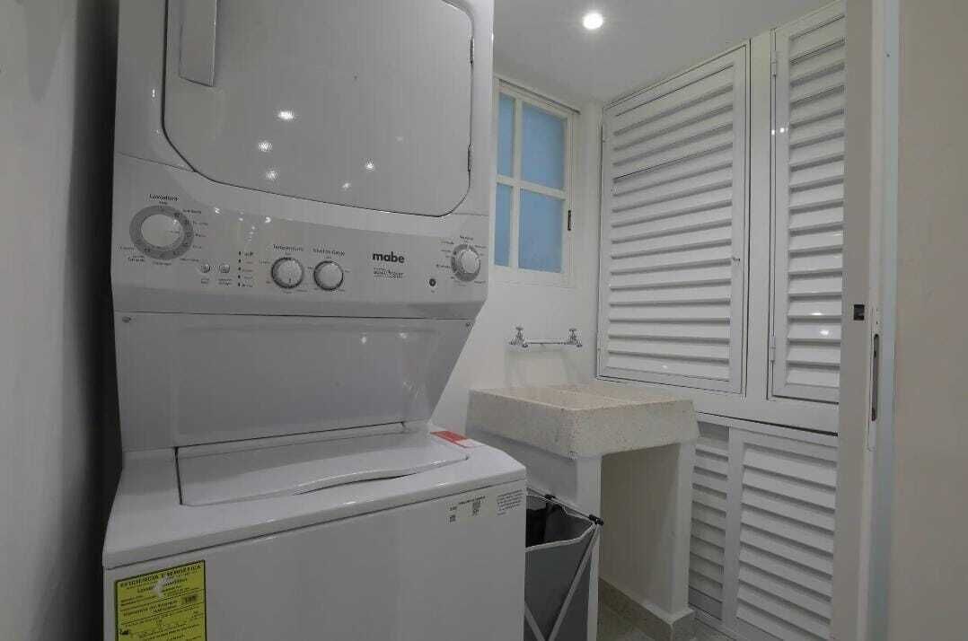 Un espacio de lavandería pequeño con lavadora, un lavabo y una ventana con persianas.