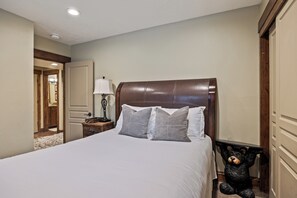 A neatly made bed with a headboard, a bedside lamp, and a bear-shaped nightstand. - Canyons Retreat: Alpine Charm, Shared Hot Tub/Pool, Sleeps 10, Cozy Fireplace (Park City)