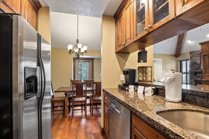 A kitchen with a stainless steel refrigerator, wooden dining table, and chairs. - Canyons Retreat: Alpine Charm, Shared Hot Tub/Pool, Sleeps 10, Cozy Fireplace (Park City)