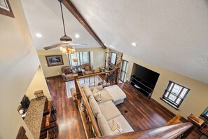 A spacious living area with a high ceiling, a fireplace, a television, and a staircase leading to an upper level. - Canyons Retreat: Alpine Charm, Shared Hot Tub/Pool, Sleeps 10, Cozy Fireplace (Park City)