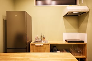 A compact kitchen with a stainless steel refrigerator, a wooden countertop, a built-in sink, and a microwave.