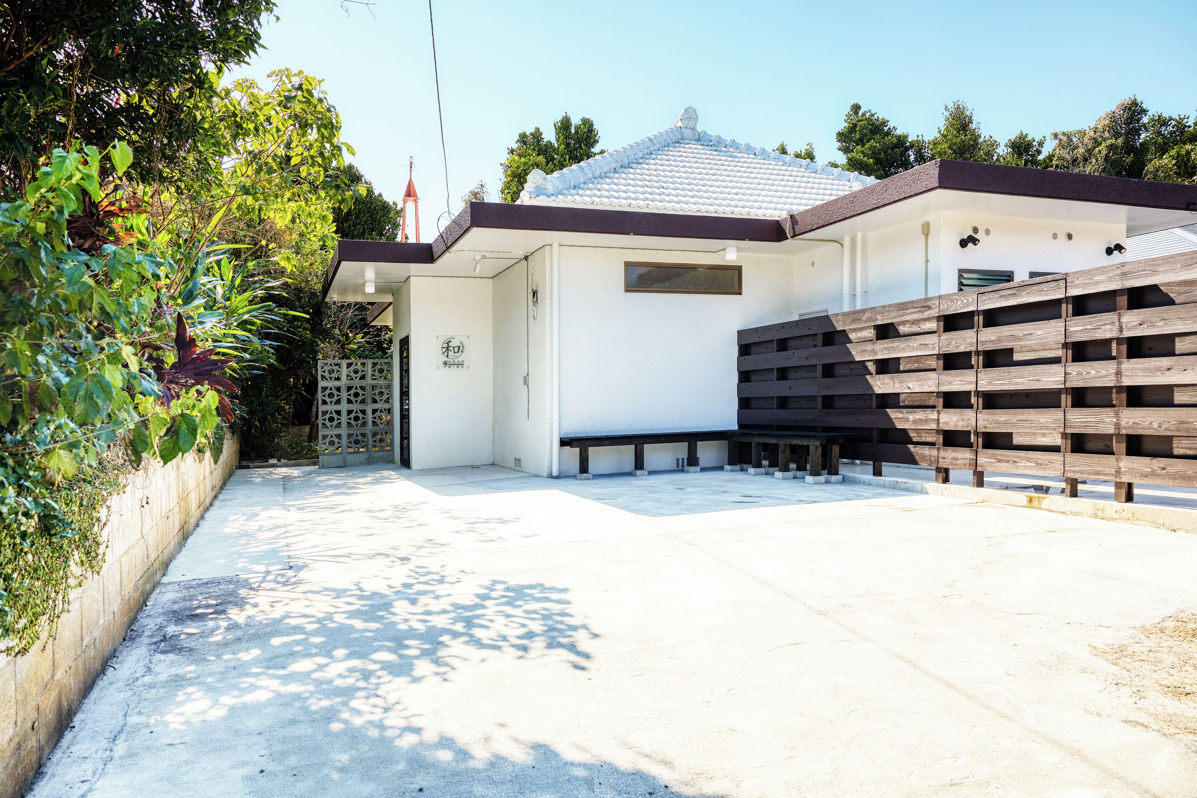 A modern building with a white exterior, a tiled roof, and a wooden fence.