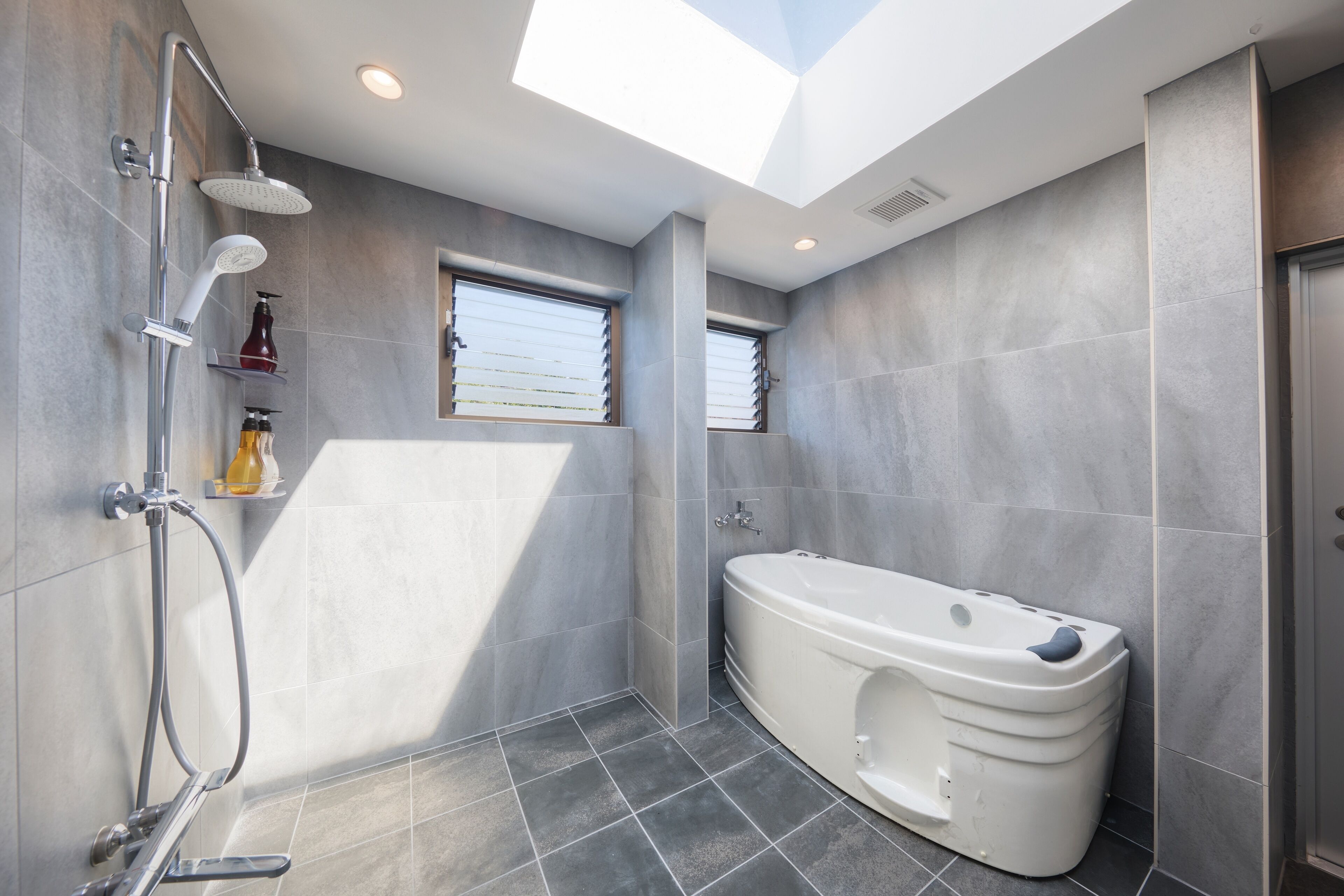 A modern bathroom with a skylight, a walk-in shower, and a freestanding bathtub.