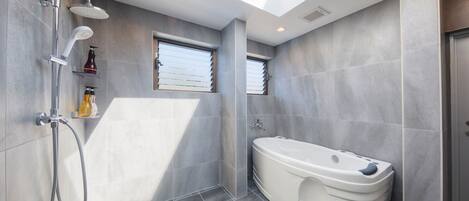 A modern bathroom with a skylight, a walk-in shower, and a freestanding bathtub.