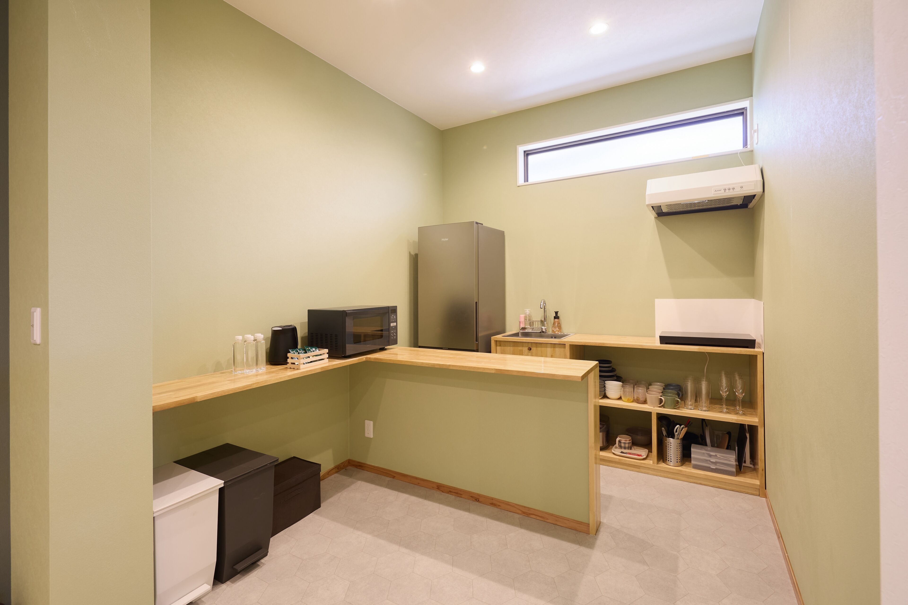 A compact kitchen with a microwave, refrigerator, and wooden counter.