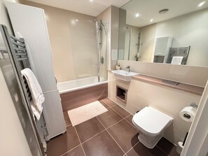 Ein modernes Badezimmer mit einer Duschkabine, einem weißen Waschbecken und einer Toilette.