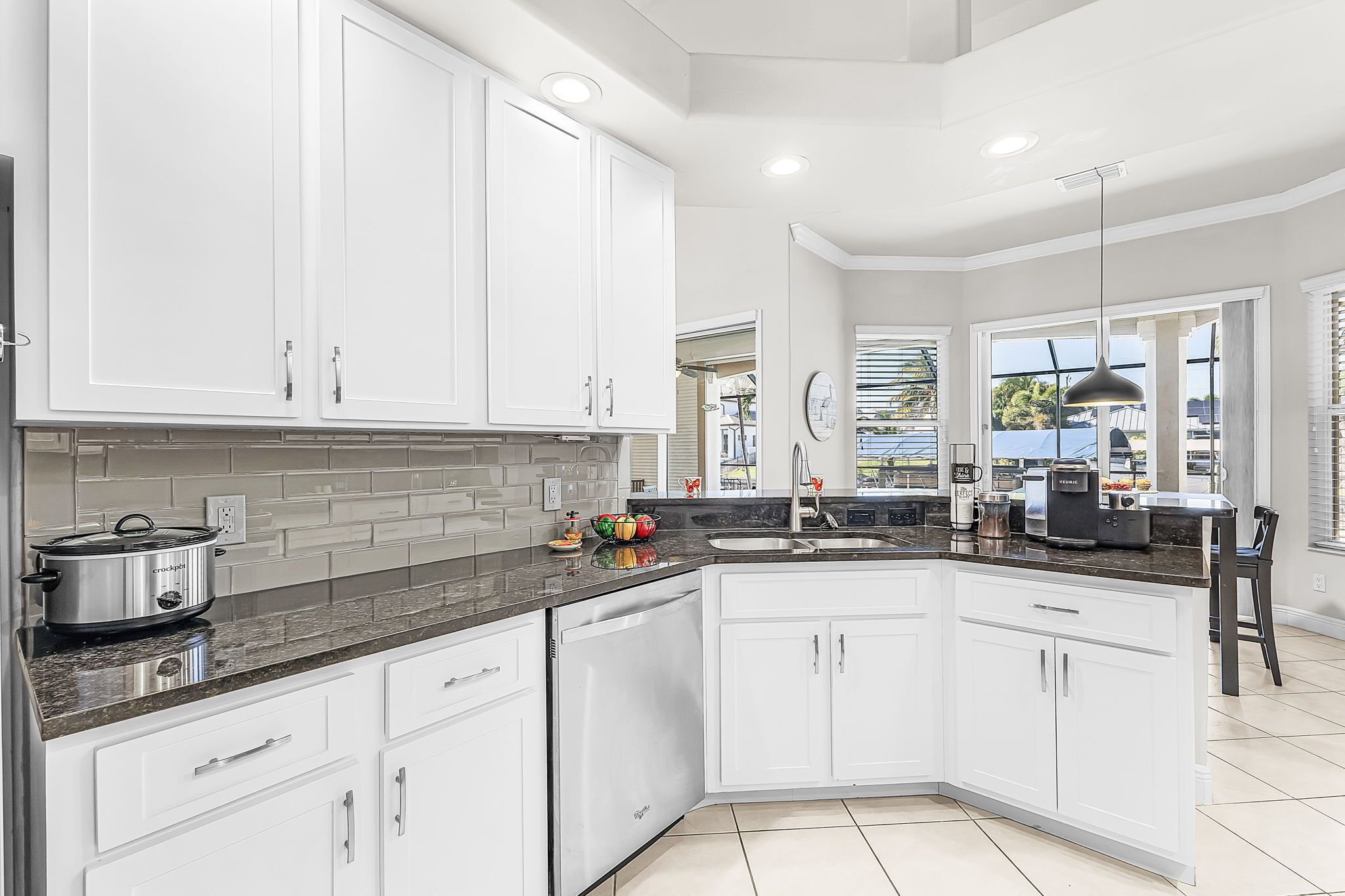A modern kitchen with white cabinets, a granite countertop, and stainless steel appliances.