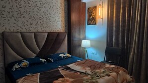 Een hotelkamer met een groot bed, een wandlamp en een gordijn.