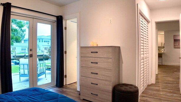 A bedroom with a bed, a dresser, and a view of the outdoors through a sliding door. - Charming Waterfront Oasis, Quiet Island Near Beach (Fort Lauderdale)