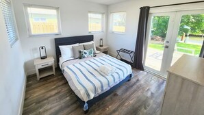 A bedroom with a bed, bedside tables, a ceiling fan, and a view of the outdoors. - Charming Waterfront Oasis, Quiet Island Near Beach (Fort Lauderdale)