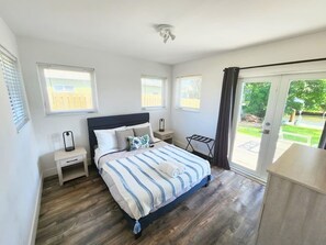 A bedroom with a bed, bedside tables, a ceiling fan, and a view of the outdoors. - Charming Waterfront Oasis, Quiet Island Near Beach (Fort Lauderdale)