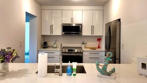 Cocina moderna con armarios blancos, electrodomésticos de acero inoxidable y una isla central con adornos.