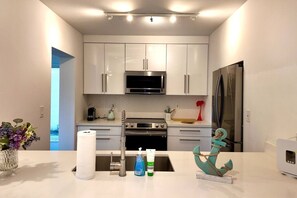 Cocina moderna con armarios blancos, electrodomésticos de acero inoxidable y una isla central con adornos.