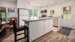 Una cocina moderna con armarios blancos, una isla central, horno empotrado y lavavajillas.