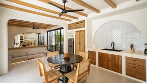 A modern kitchen with a round dining table, wooden chairs, and a built-in sink. - Palmera Aalto Bingin (Pecatu)