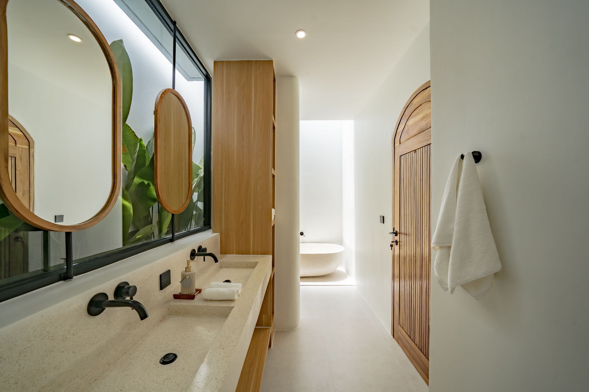 Un baño moderno con un espejo grande, dos lavamanos, un mueble de tocador de madera y un inodoro.