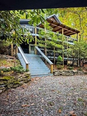 Ein modernes Haus mit einer Holztreppe, die zu einer überdachten Veranda führt.