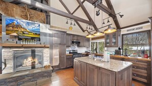 A spacious kitchen with a large island, stone fireplace, and a high ceiling with exposed beams. - 3 BR Beech Mtn Basecamp: 2 Mi to Resort, Fireplace & Firepit (Beech Mountain)
