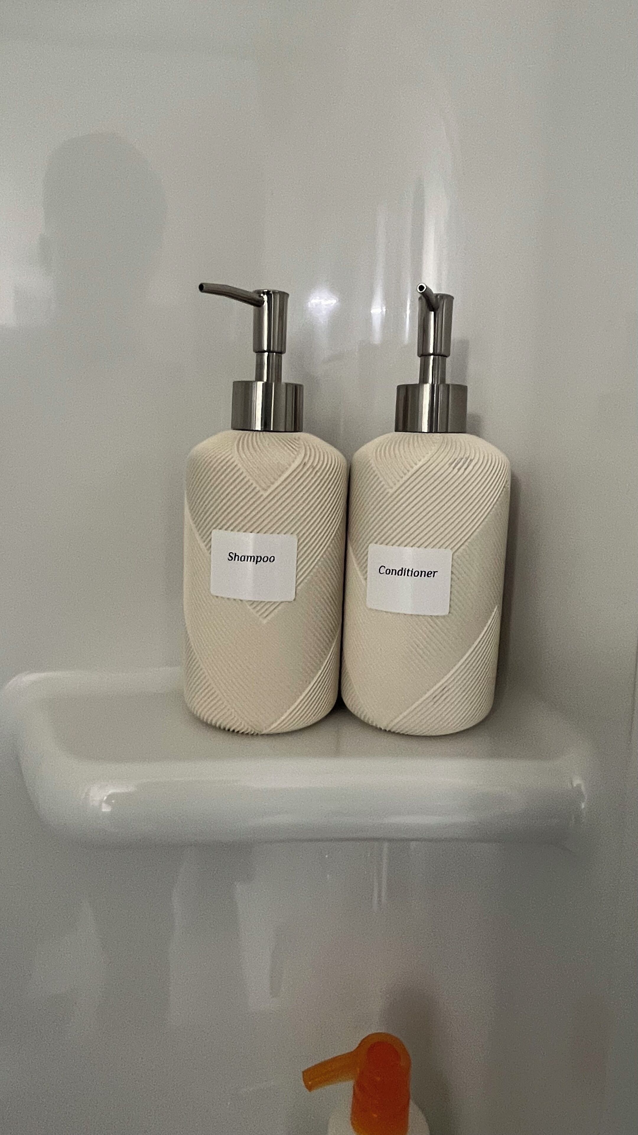 To toilettens beholdere med pumpe på en hvid hylde.