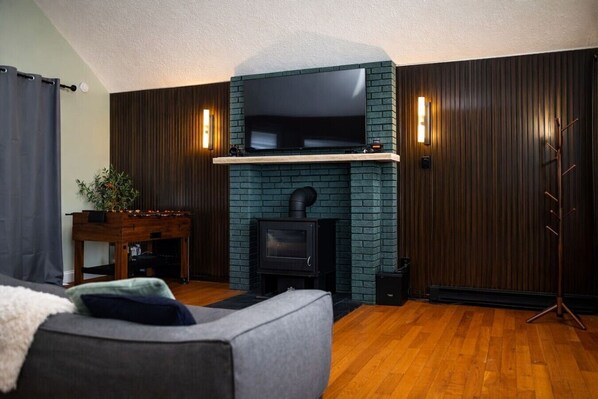 A living room with a fireplace, a television mounted above it, and a sofa.